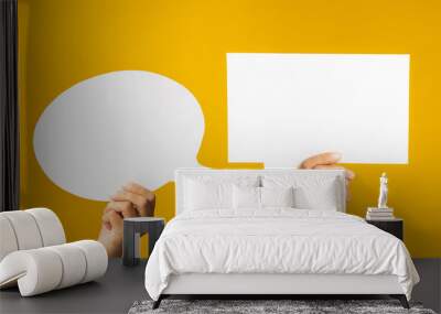 Speech bubble concept. Close-up of hands holding of two empty white speech balloons are over a yellow background with copy space for text Wall mural