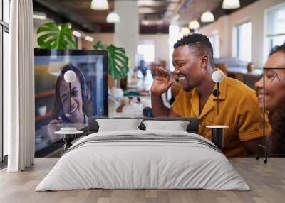 A Black man waves to his colleague on a video call from his office Wall mural