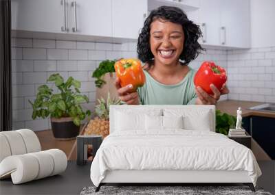 A young multi-ethnic woman holds two sweet peppers out of fresh veg delivery box Wall mural