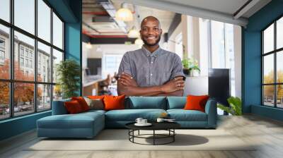 An attractive Black man stands with arms crossed in creative office workplace Wall mural