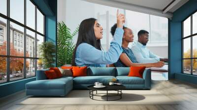 Young business woman raises hand in boardroom meeting to ask question Wall mural