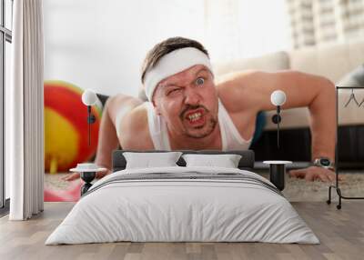 Funny grimacing man making push-ups home Wall mural