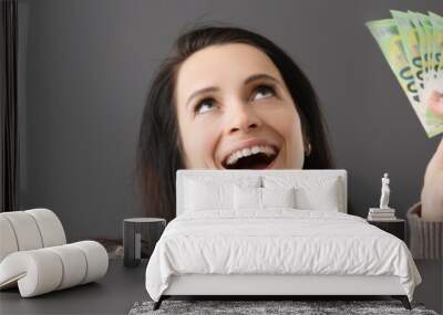 Joyful happy woman holds cash in hand Wall mural