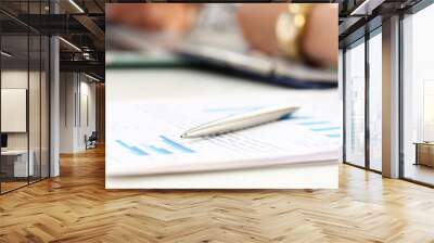 Silver pen lying at worktable while busynesspeople solving important problem in background Wall mural