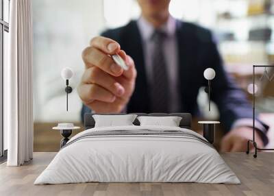 Successful manager points pen to camera sitting at table Wall mural