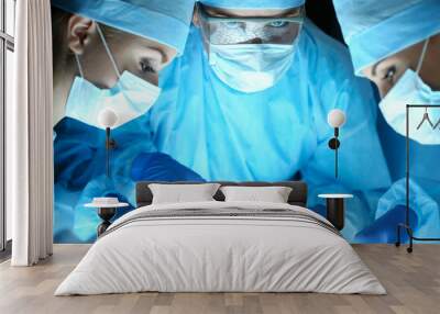 Three surgeons at work operating in surgical theatre Wall mural