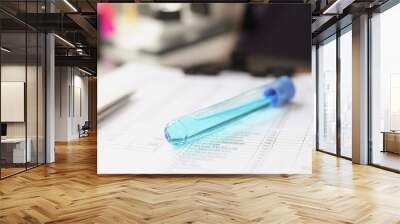 Vial of blue liquid lies on test results document closeup Wall mural