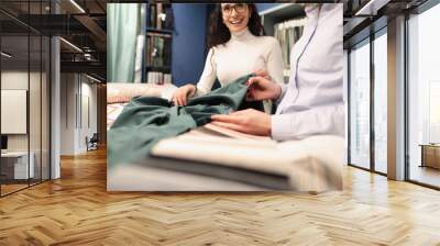 Woman designer showing client green fabric in curtains salon Wall mural