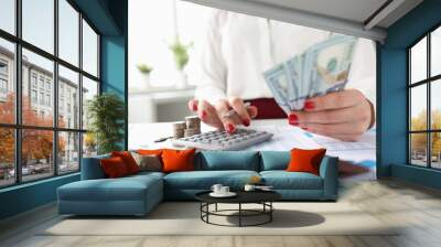 Woman holds American banknotes in her hands and works on calculator Wall mural