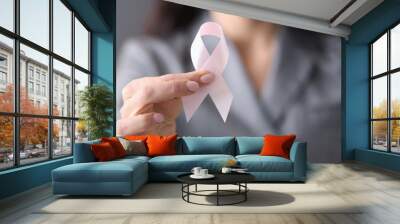 Woman in gray business suit holding pink ribbon in her hands closeup Wall mural