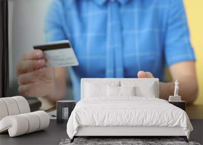 Woman sitting at table with documents and holding mobile phone and credit bank card in her hands closeup Wall mural