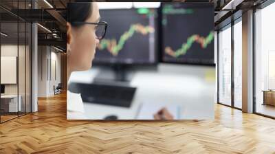 Woman with glasses looking at computer screen with graphs Wall mural