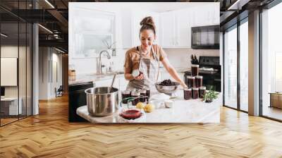 Woman canning homemade blackberry jam in home kitchen Wall mural