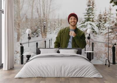 Young Trendy Man in Green Bomber Jacket Enjoying the Winter Snow on a Small Bridge in Colorado Wall mural