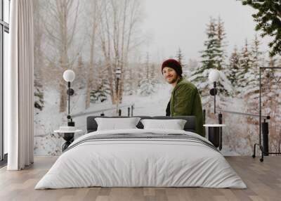 Young Trendy Man in Green Bomber Jacket Enjoying the Winter Snow on a Small Bridge in Colorado Wall mural