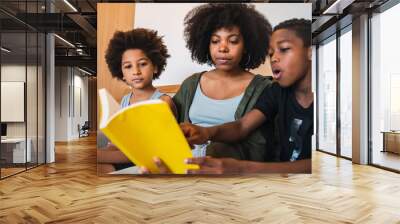 Afro mother reading a book to her children. Wall mural