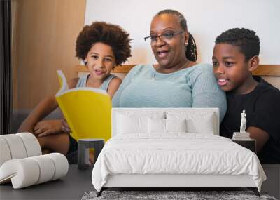 Grandmother reading a book to grandchildren. Wall mural