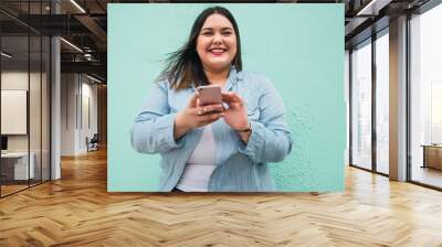 Young plus size woman using her mobile phone. Wall mural