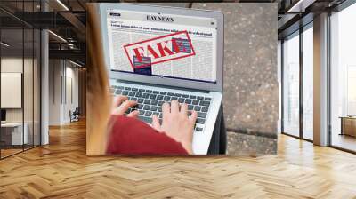 Young woman reading digital fake news on laptop Wall mural