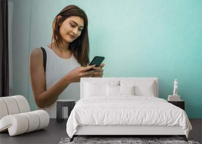 Young woman using her mobile phone. Wall mural