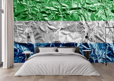 Sierra Leone flag depicted in paint colors on shiny crumpled aluminium foil closeup. Textured banner on rough background Wall mural