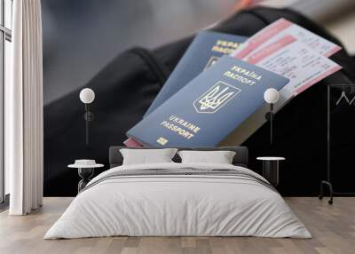 Two ukrainian biometrical passports with air flight tickets on black touristic backpack close up Wall mural