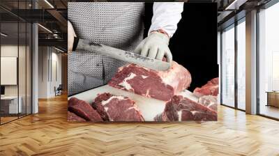 Close up of minced meat pieces and butcher's male hands in special gloves cutting with knife. Meat pork or beef on the butcher's table. Worker in white uniform and special steel apron. Wall mural