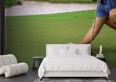 a golfer lining up is golf ball to putt Wall mural