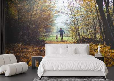 happy dog and man playing in autumn forest Wall mural