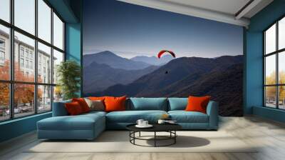 red paraglider flying over mountain Wall mural