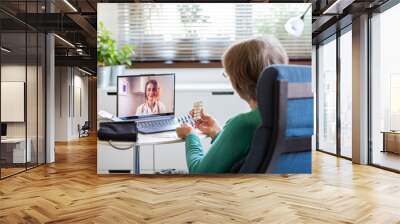 telemedicine concept elderly woman speaking to her doctor online and taking her blood pressure Wall mural