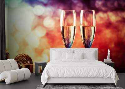 two champagne glasses against holiday lights and fireworks - new year celebration Wall mural