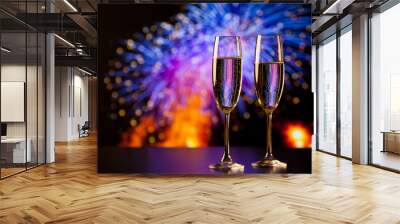 two champagne glasses against holiday lights and fireworks - new year celebration Wall mural