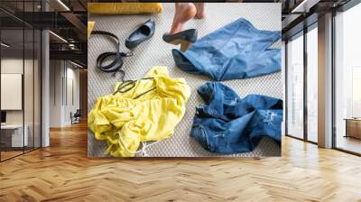 yellow and blue pieces of clothes on the floor woman undressing Wall mural