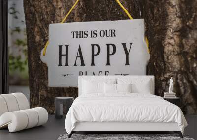 Outdoor sign hung on a tree reading, This is our happy place Wall mural