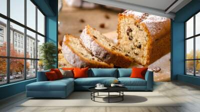 A homemade cake with raisins and powdered sugar is cut on wooden table. White napkin Wall mural