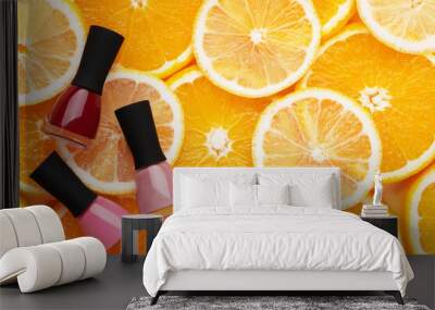 Multicolored nail polishes on a citrus background top view. Tools for professional manicure and pedicure pink and red on oranges and lemons. Summer concept, female beauty Wall mural