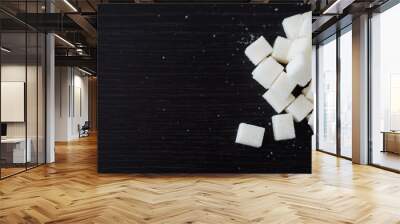 White sugar cubes piled in heap on the black desk Wall mural