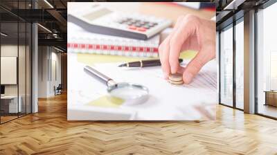 man is putting coins on stock market papers.financial background Wall mural