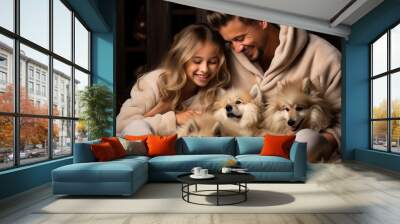 A young loving couple cuddling with their two fluffy white dogs on a cozy winter night in their home. Wall mural