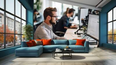 Businessman working on computer in office. Business people in the background Wall mural