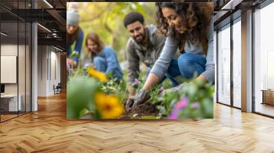 Group of diverse young people planting flowers together in the garden Wall mural