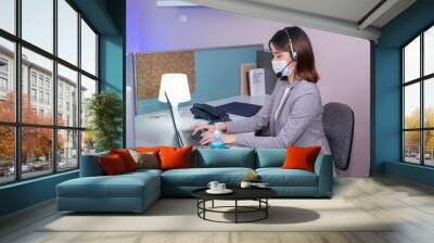 New normal style, Young businesswoman wearing face mask and using Sanitizer hand gel while working on a computer in the office. Wall mural