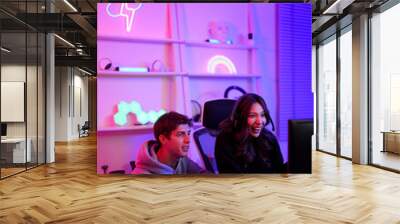 Couple streamer lover boy and girl use joystick for playing video game together hobby in the weekend at entertainment violet neon light room vertical style Wall mural