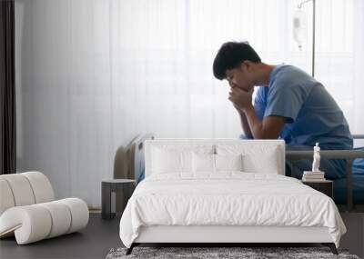 Depression disorder patient asian young male sitting alone and thinking about his life and live on hospital bed with blue uniform in the special VIP room Wall mural