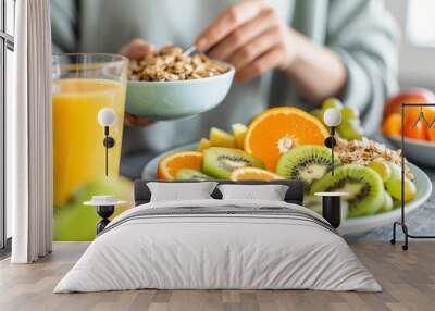 A person is eating a bowl of cereal and drinking orange juice Wall mural