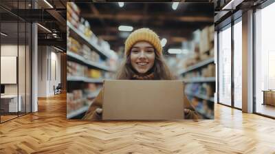 A woman is smiling and holding a cardboard box in a grocery store Wall mural