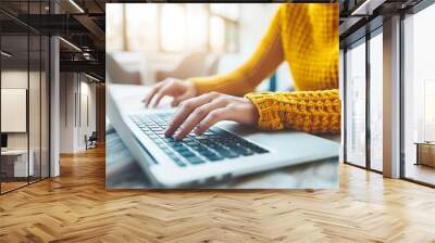 A woman is typing on a laptop in a yellow sweater Wall mural