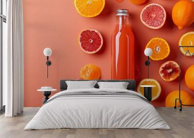 Bottle of grapefruit juice surrounded by lemons, grapefruits and plants on an orange background Wall mural