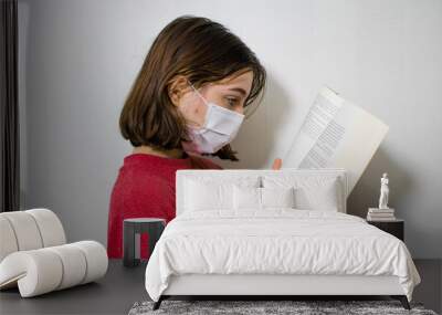 A person with a mask reading a book, a woman with a mask reading a book, reading books with a face mask, amazed woman reading book in a mask Wall mural